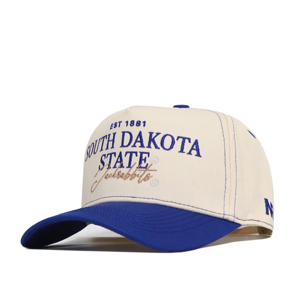 A cream and blue snapback South Dakota State Vintage Hat by No Rivals, featuring “South Dakota State Jackrabbits EST 1881” officially licensed and embroidered on the front in blue and gold letters.