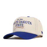 A cream and blue snapback South Dakota State Vintage Hat by No Rivals, featuring “South Dakota State Jackrabbits EST 1881” officially licensed and embroidered on the front in blue and gold letters.