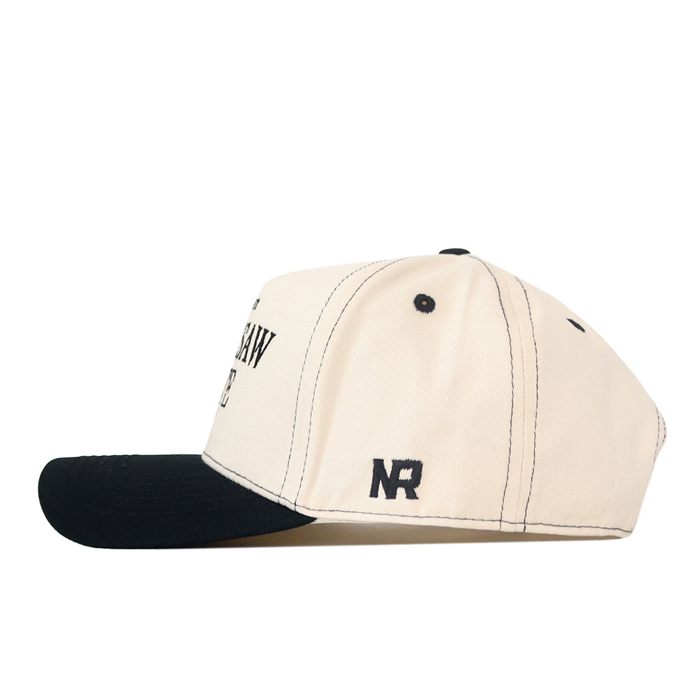 Side view of a beige Kennesaw State Owls Vintage Hat by No Rivals, featuring a black snapback brim, black stitching and eyelets, and an embroidered NR logo in black on the side.