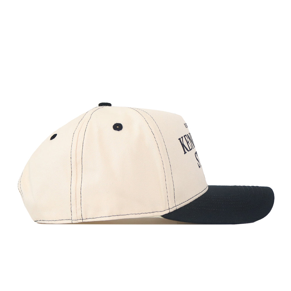 A beige No Rivals Kennesaw State Owls Vintage Hat with black stitching, black eyelets, and a curved black brim, featuring an embroidered logo on the front, shown from the side against a white background.