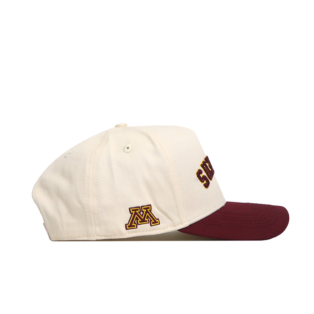 The Minnesota Golden Gophers Upside Down Gophers Hat - Classic by No Rivals is a cream-colored snapback baseball cap featuring a maroon brim. A yellow and maroon M logo appears on the side, highlighting its official Minnesota Golden Gophers design. The word SCHEELS is partially visible on the front of this officially licensed hat.