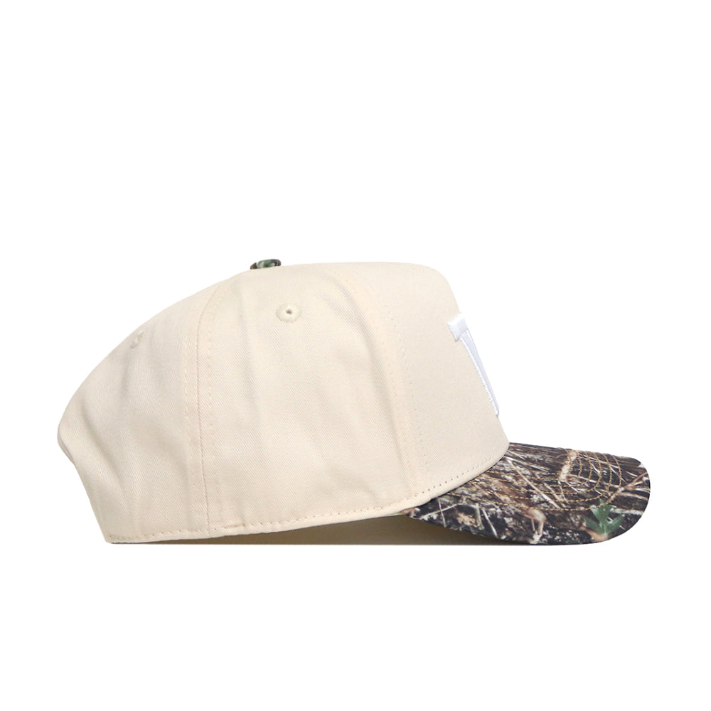 The No Rivals Washington Camo Connector Hat features a beige snapback design with a camouflage-patterned brim and embroidered logos, displayed from the side on a white background.