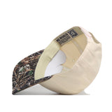 The Washington Camo Connector Hat by No Rivals is flipped over to display its interior lining, tags, and an inner label reading NO RIVALS. The hat features a beige snapback design with a camouflage-patterned brim.