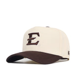 The No Rivals ETSU Espresso Hat is a beige snapback with a structured fit, featuring a brown brim, a large embroidered brown “E” on the front, side brown logo/text, and crafted from high-quality cotton for comfort.