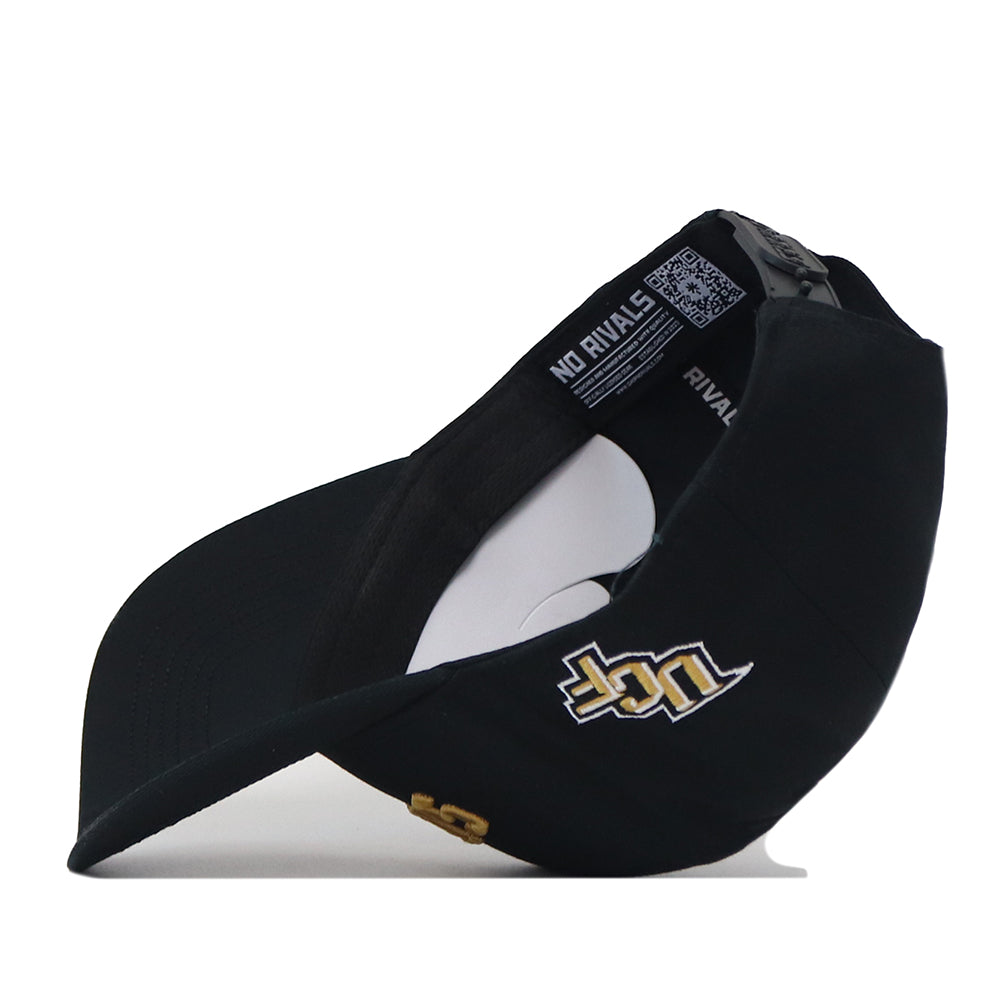 The UCF Knights | Upside Down Knights Hat - Blackout by No Rivals is a black baseball cap displayed from the side, showcasing a gold and white embroidered logo, curved brim, and “NO RIVALS” text on the inner band. This officially licensed UCF Knights hat features a classic snapback closure for a comfortable fit.