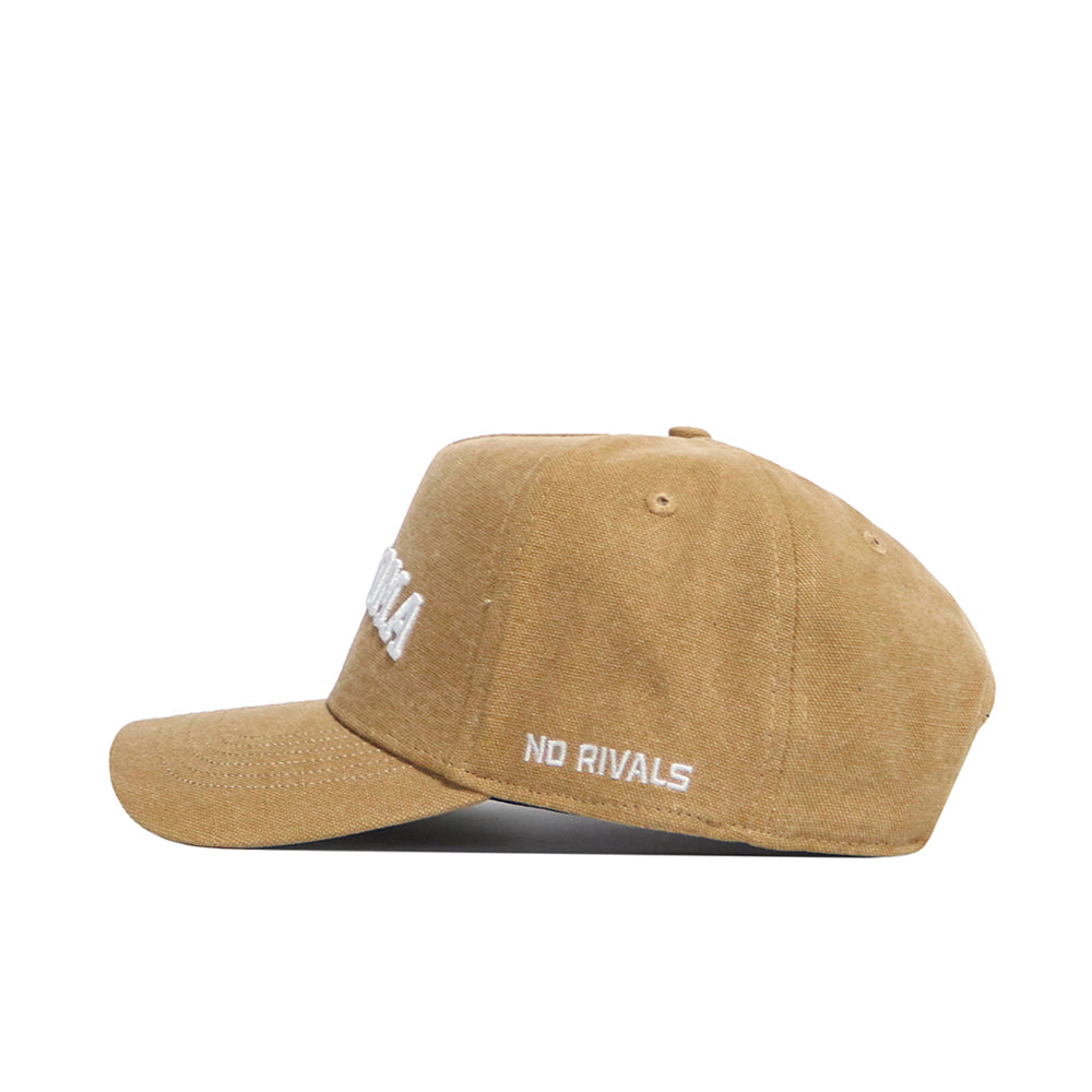 The Oklahoma Rustic Hat by No Rivals is a tan cotton canvas hat with white "NO RIVALS" embroidery on the side, a structured fit, curved brim, visible stitching, and classic style—ideal for everyday wear.