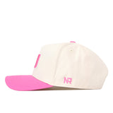 A side profile view of the Miami Pink Out Hat by No Rivals, featuring a white base with a pink brim and pink “NR” initials embroidered on the side, displayed on a white background. This officially licensed snapback combines style and comfort, making it perfect for everyday wear.