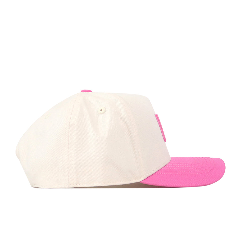 The Miami Pink Out Hat by No Rivals is a cream-colored snapback baseball cap featuring a pink brim and a matching pink top button, displayed from the side.