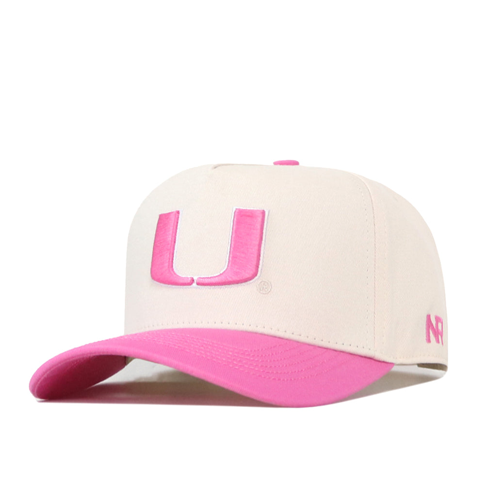 Introducing the Miami Pink Out Hat by No Rivals—a white snapback baseball cap featuring a bold pink letter U on the front and a matching pink brim. The signature NR initials are embroidered on the left side of the cap. This stylish design makes it a meaningful breast cancer awareness hat, perfect for showing your support with flair.