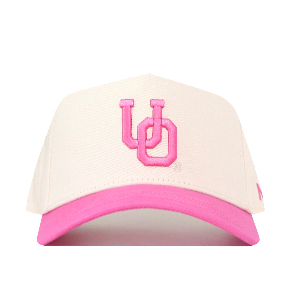 The Oregon Pink Out Hat by No Rivals is a stylish white baseball cap made from high-quality cotton, featuring a pink brim and pink embroidered “UO” on the front—making it the perfect snapback for showing your support as a breast cancer hat.