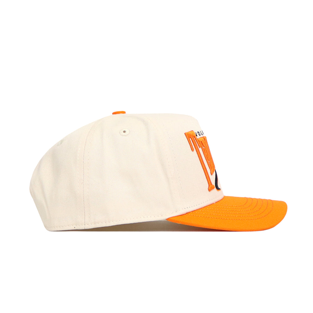The No Rivals Tennessee Stride Hat is a cream snapback with an orange brim and top button, shown from the side. Made of premium cotton, it sports a striking orange and black embroidered front logo.
