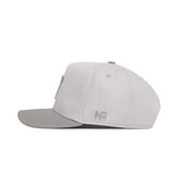 The No Rivals Tennessee Graphite Hat is a light gray structured cap with a flat brim and NR embroidered on the left side, showcasing sharp stitched graphics. It's photographed from the side against a white background.