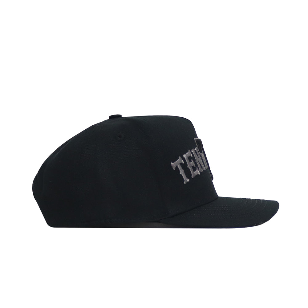 The No Rivals Tennessee Night Mode Hat is a black snapback with a flat brim and classic structured fit, made from high-quality cotton. It features raised, embroidered white text on the front panel and is shown from the side.