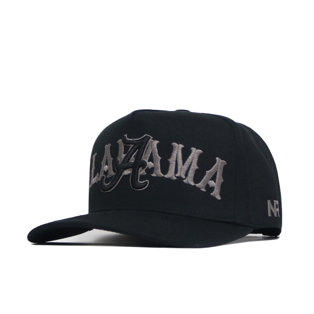 The Alabama Night Mode Hat by No Rivals is a black snapback with a flat brim, ALAYZAMA in large gray gothic embroidery on the front, and NR stitched on the side. Made from high-quality cotton with a structured fit.