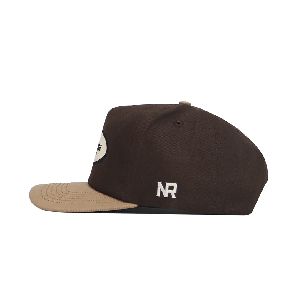 Side view of the No Rivals Alabama Neutral Patch Hat in brown with a beige brim, oval front patch, and white "NR" embroidery on the side. Its structured fit guarantees lasting comfort.