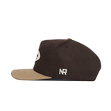 Side view of the No Rivals Alabama Neutral Patch Hat in brown with a beige brim, oval front patch, and white "NR" embroidery on the side. Its structured fit guarantees lasting comfort.