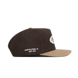 The Alabama Neutral Patch Hat by No Rivals features a brown and tan snapback design with "Tuscaloosa, AL Est. 1871" embroidered in white on the side, a beige front brim, and high-quality cotton for a structured fit.