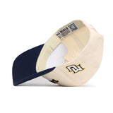 The Upside Down MARQUETTE Hat by No Rivals, shown in beige and navy, is a cotton-canvas snap back. It displays the inner NO RIVALS label and an embroidered logo on the exterior.