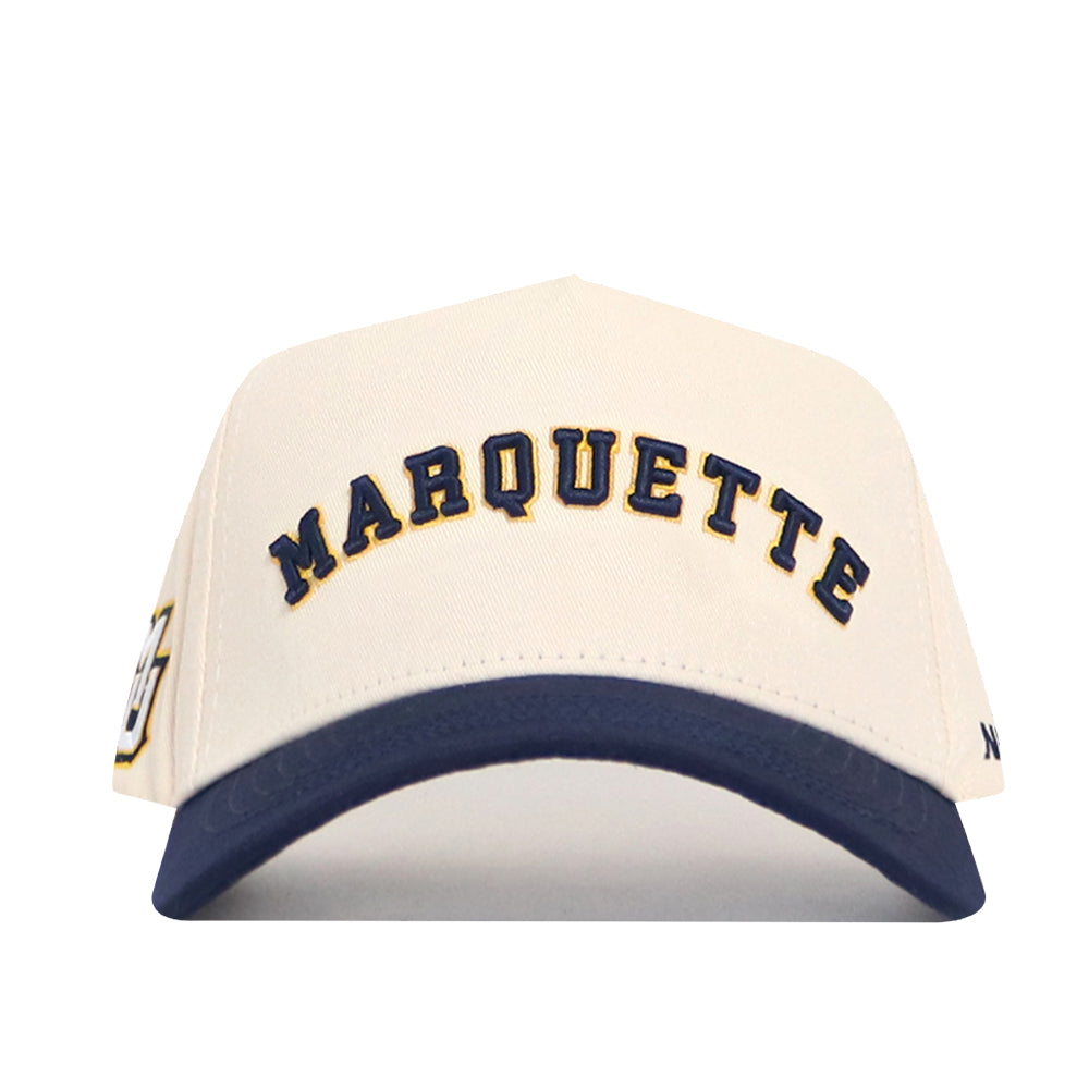The Right Side Up MARQUETTE Hat by No Rivals features a cream cotton-canvas body, navy blue brim, and structured fit with "MARQUETTE" embroidered in navy on the front.
