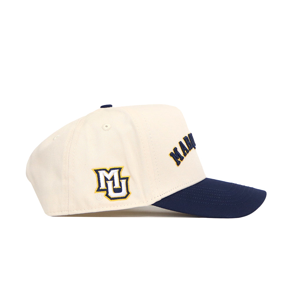 The No Rivals Right Side Up MARQUETTE Hat - Classic Colors is a cream cotton-canvas snapback with a navy brim, partial MARQUETTE text on the front, and MU letters in yellow and blue on the side for classic collegiate style.