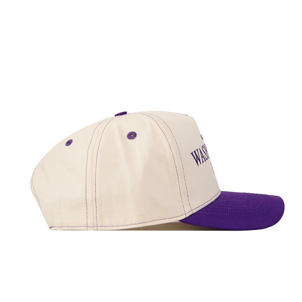 The No Rivals Washington Huskies Vintage Hat is crafted from high-quality cotton in beige, featuring a purple brim and matching purple accents such as stitching and ventilation holes. An embroidered purple logo with partial text appears on the side, while a snapback closure ensures a comfortable fit.
