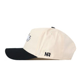 A cream-colored South Dakota State Espresso Hat by No Rivals, featuring a black brim and a bold black NR embroidered near the back, viewed from the side—making it the perfect snapback for your gameday fit.