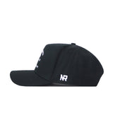 The West Virginia Outlaw Hat by No Rivals is a black baseball cap shown from the side, featuring a white embroidered NR logo on the back panel and an adjustable snap back for a comfortable fit.