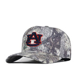 The No Rivals Auburn Outland Hat is a camouflage baseball cap featuring a red and navy embroidered AU logo on the front, representing Auburn University. Made from high-quality cotton, the hat is displayed at an angle to highlight its detailed logo and part of the brim.