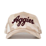 The No Rivals Texas A&M Script Sand Camo Hat - Unstructured is a beige camouflage baseball cap crafted from high-quality cotton, showcasing “Aggies” embroidered in dark red cursive on the front and finished with a convenient snap-back closure.