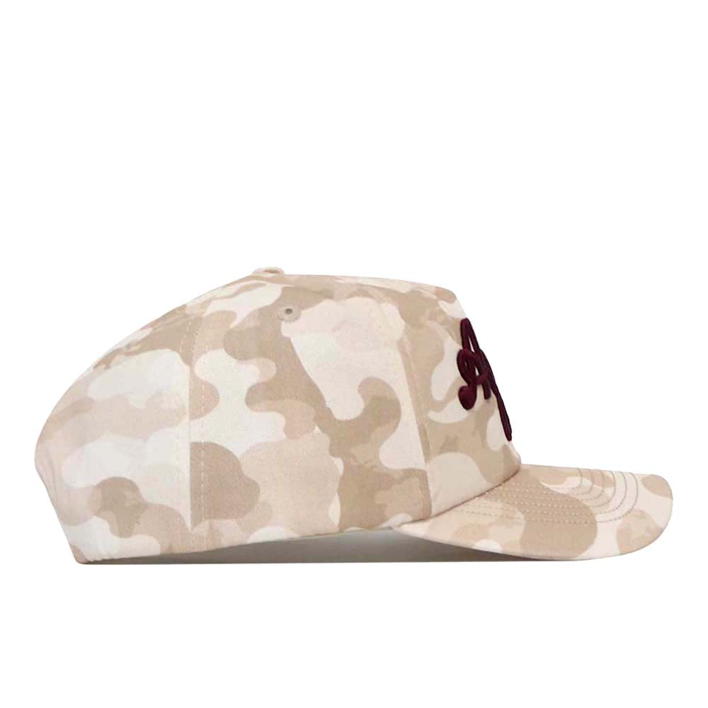 The No Rivals Texas A&M Script Sand Camo Hat - Unstructured is shown from the side, featuring a tan and beige camouflage pattern, a curved brim, and a dark embroidered Texas A&M script logo on the front. This unstructured cap offers a relaxed fit for casual style.