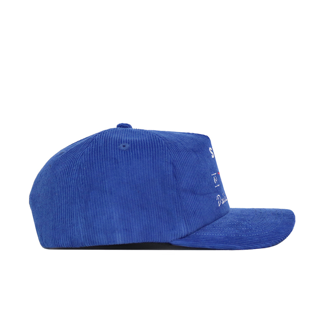 A side view of the SMU Vintage Cord Hat in blue showcases its ridged corduroy texture. The front has small white embroidery, and the adjustable side and brim are fully visible.