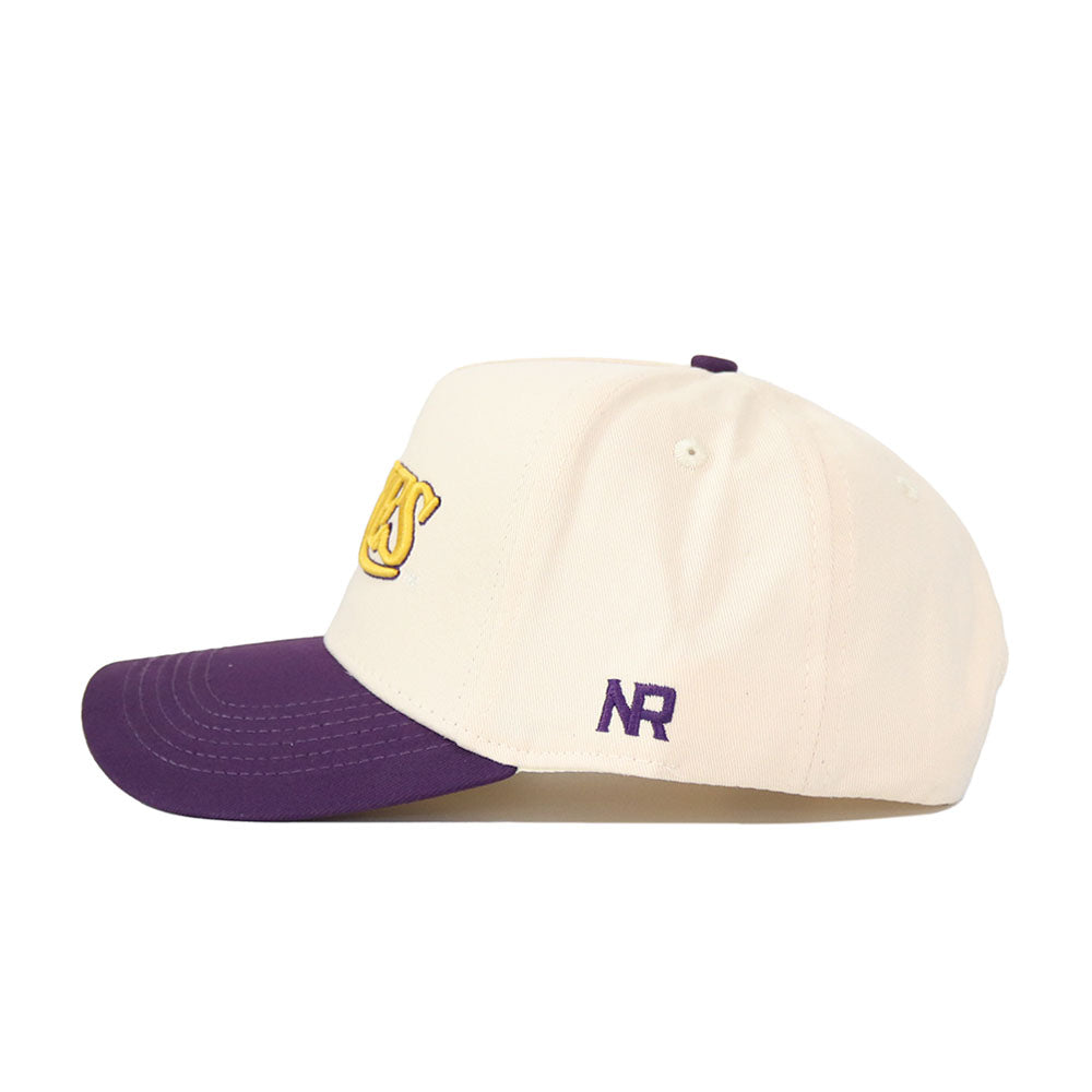 The No Rivals JMU Vintage Wordmark Hat (B2B) is a cream baseball cap with a purple brim, yellow embroidered front text, and dark blue NR letters on the side. Its unstructured fit and snapback make it one size fits most.