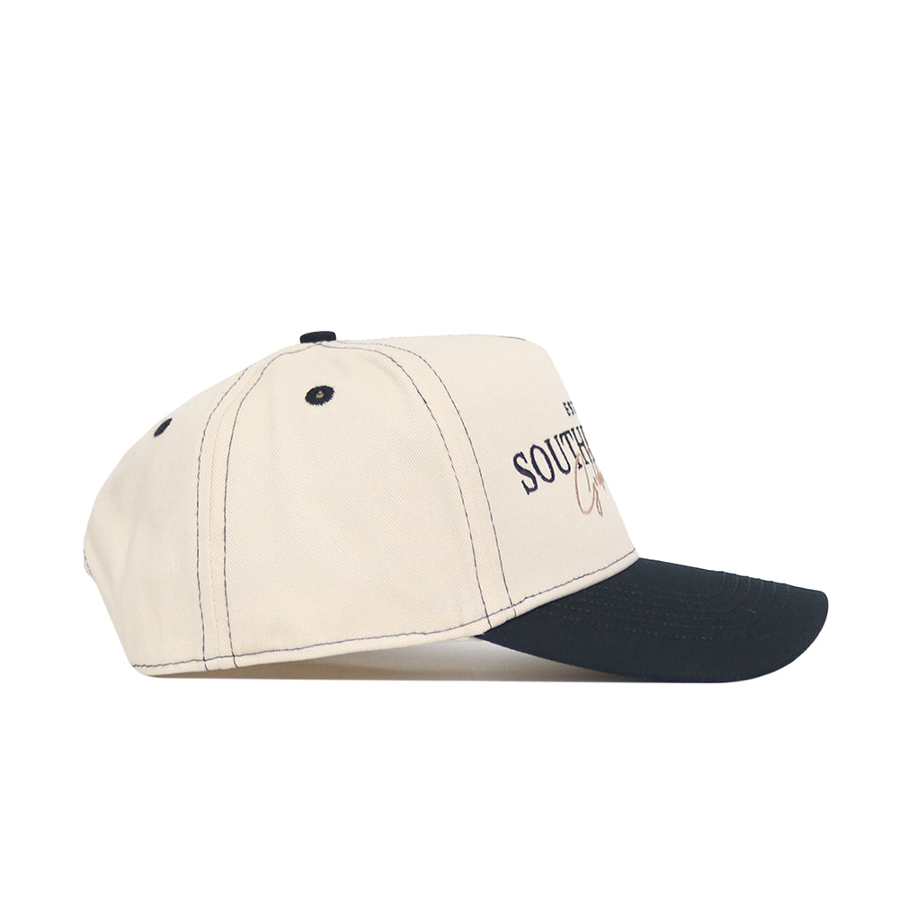The Southern Miss Vintage Hat by No Rivals is a beige snapback with a black curved brim, black stitching, and an embroidered logo featuring partial text on the side.