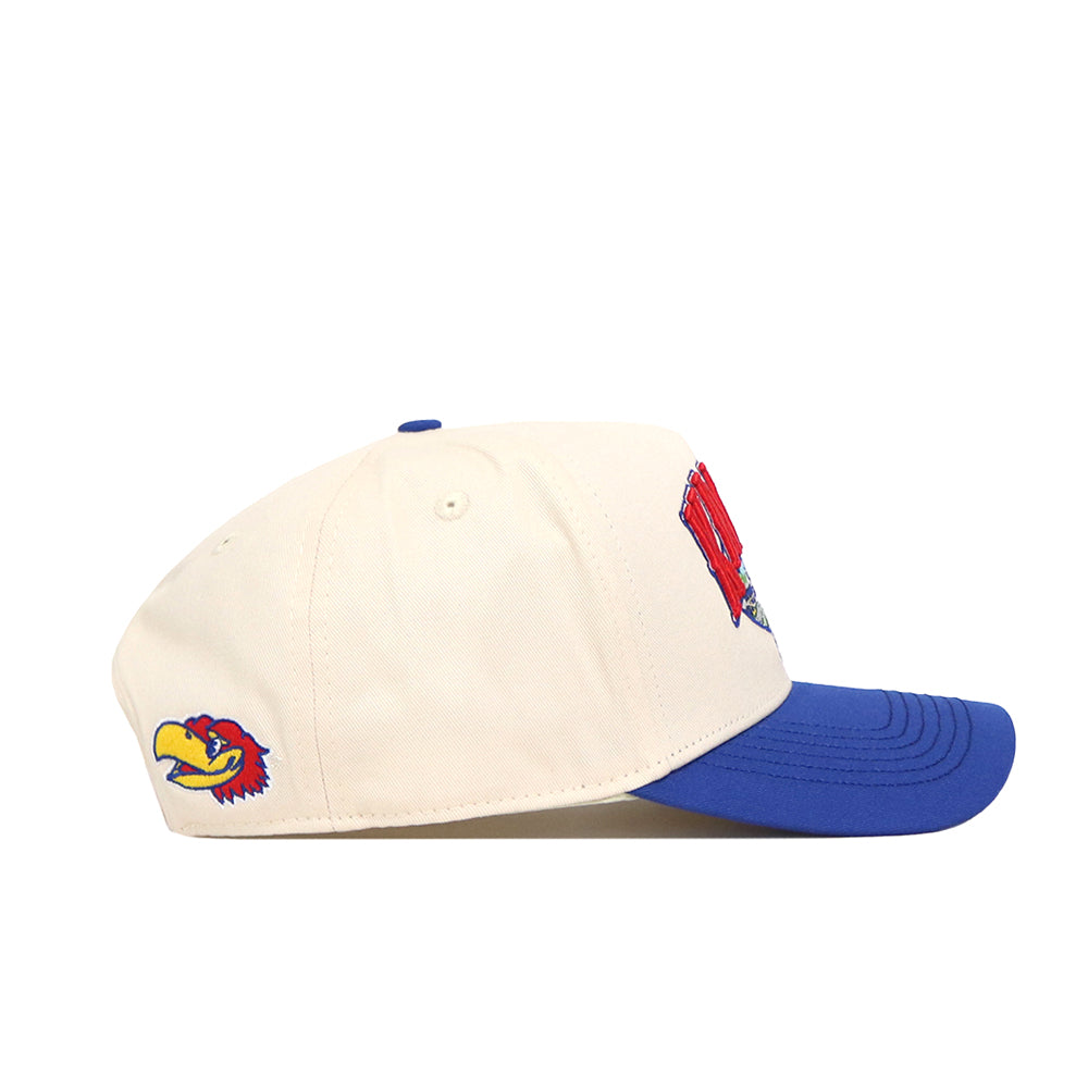 The No Rivals Kansas Jayhawks Stadium Hat is a cream-colored baseball cap with a blue brim, featuring officially licensed embroidered bird logos on the side, red text and a bird design on the front, and a snap back closure.