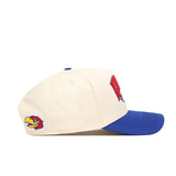The No Rivals Kansas Jayhawks Stadium Hat is a cream-colored baseball cap with a blue brim, featuring officially licensed embroidered bird logos on the side, red text and a bird design on the front, and a snap back closure.