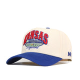 The Kansas Jayhawks Stadium Hat by No Rivals is an officially licensed snapback featuring a cream crown with a blue brim. The front displays finely embroidered red Kansas lettering, a stadium graphic, and "Jayhawks" in blue script, while the right side showcases the signature blue NR logo for authentic team style.