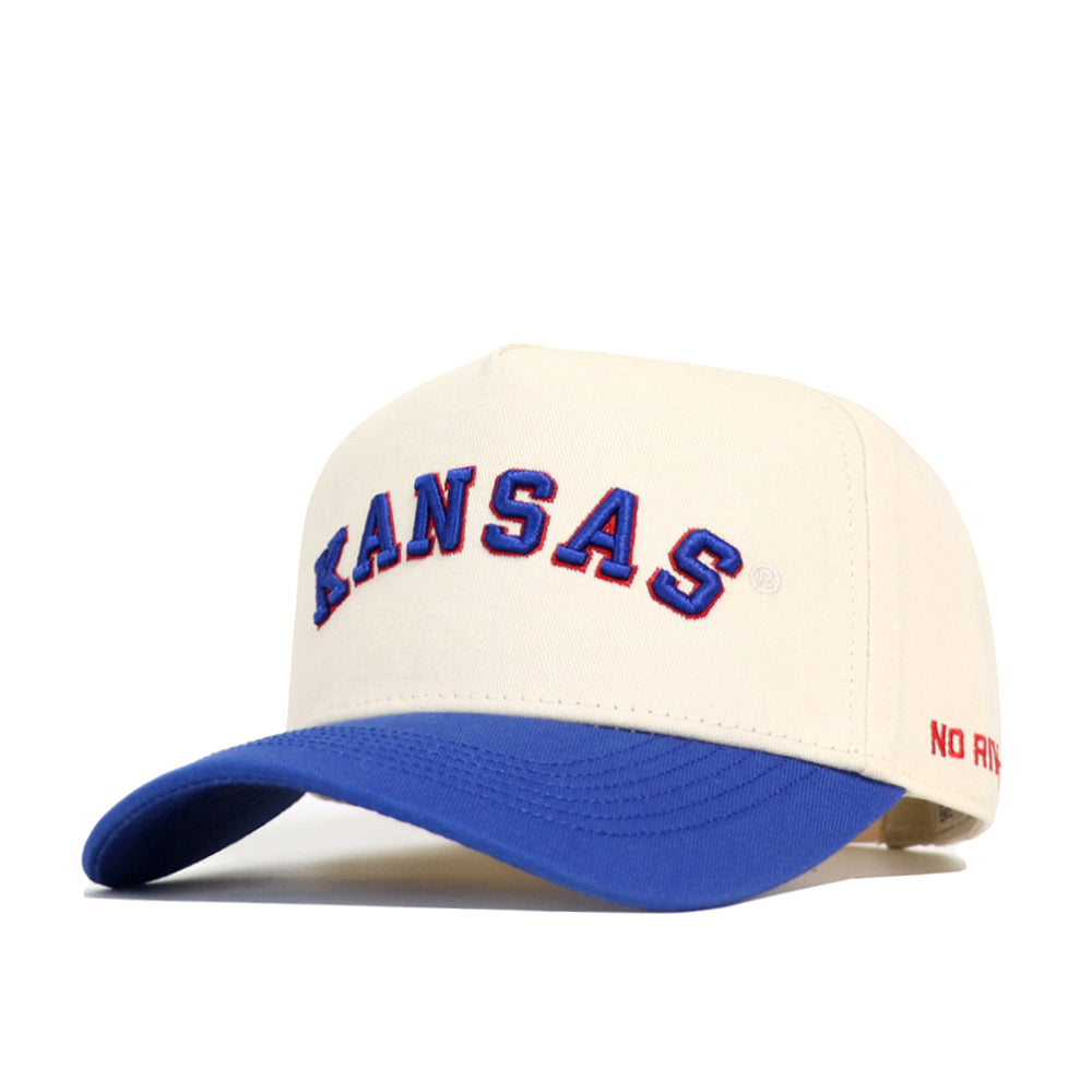 The Right Side Up KANSAS Hat by No Rivals features a cream-colored structured snapback, blue visor, KANSAS embroidered in blue/red on the front, and red NO RIV text on the side—perfect for Kansas Jayhawks fans.