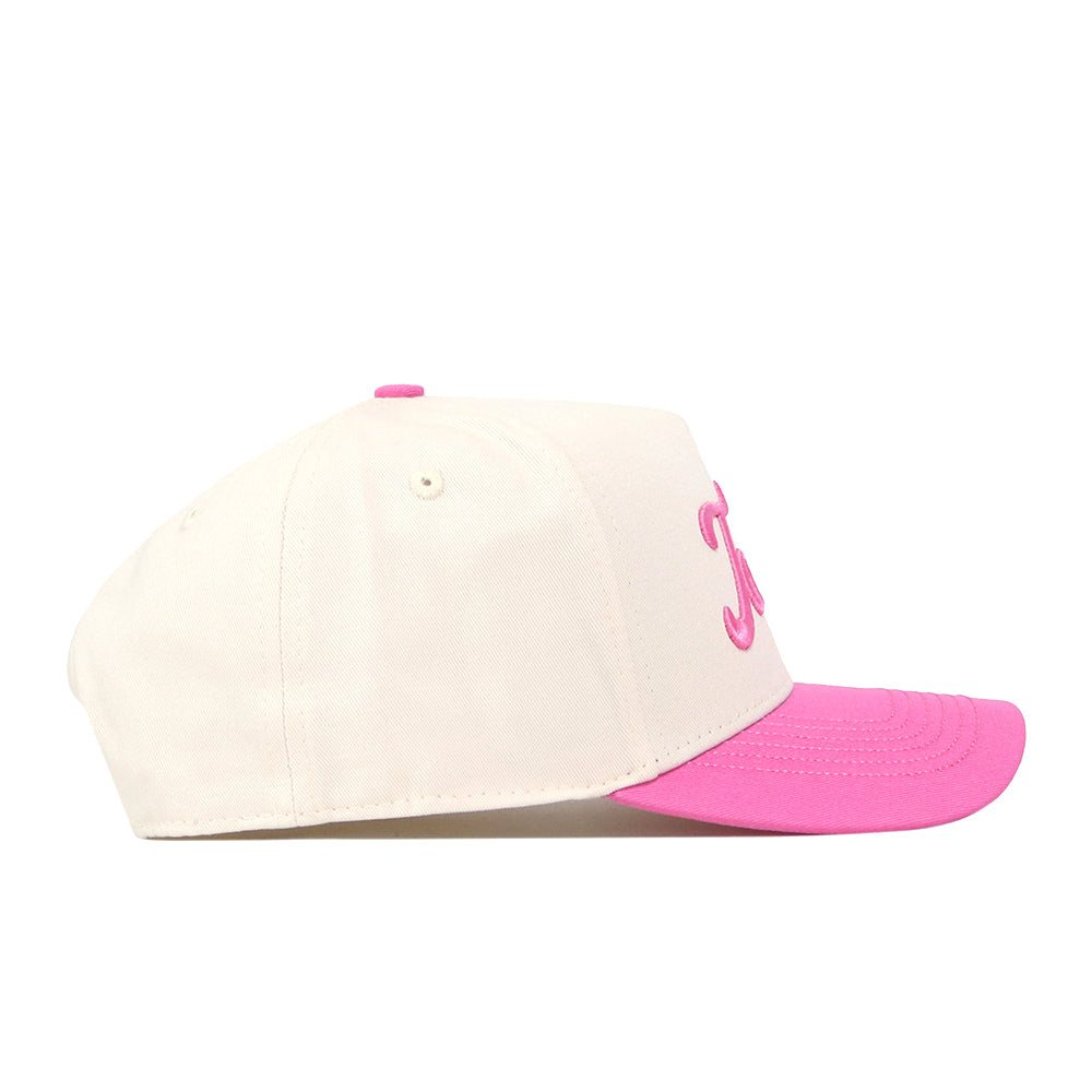The Texas Pink Out Hat by No Rivals is a cream-colored, officially licensed snapback baseball cap featuring a pink brim and pink embroidered text on the front, shown from the side against a white background—making it the perfect hat to show your support for breast cancer awareness.