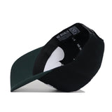 The Michigan State Tailgate Hat by No Rivals is a black and green snapback shown upside down, revealing its interior with a white cardboard insert, labels featuring "NO RIVALS," and a QR code. Made of high-quality cotton for a structured fit.