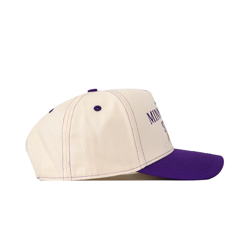 A cream-colored, officially licensed Minnesota State Mankato Vintage Hat by No Rivals, featuring a purple brim and purple stitched details with an embroidered logo, displayed from a side-angle view.