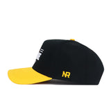 The App State Tailgate Hat by No Rivals is a black structured snapback with a curved yellow brim, yellow NR embroidery on the side, and partially visible white front lettering for an officially licensed bold look.