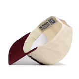 The No Rivals Texas A&M Stride Hat is a cream cap with a maroon brim, shown from below to display its interior label, size adjuster, and QR code on the sweatband—crafted from high quality cotton for a structured fit.