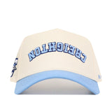 The No Rivals Upside Down CREIGHTON Hat - Light Blue features beige and light blue cotton-canvas, a structured fit, and "CREIGHTON" embroidered upside down in blue on the front.