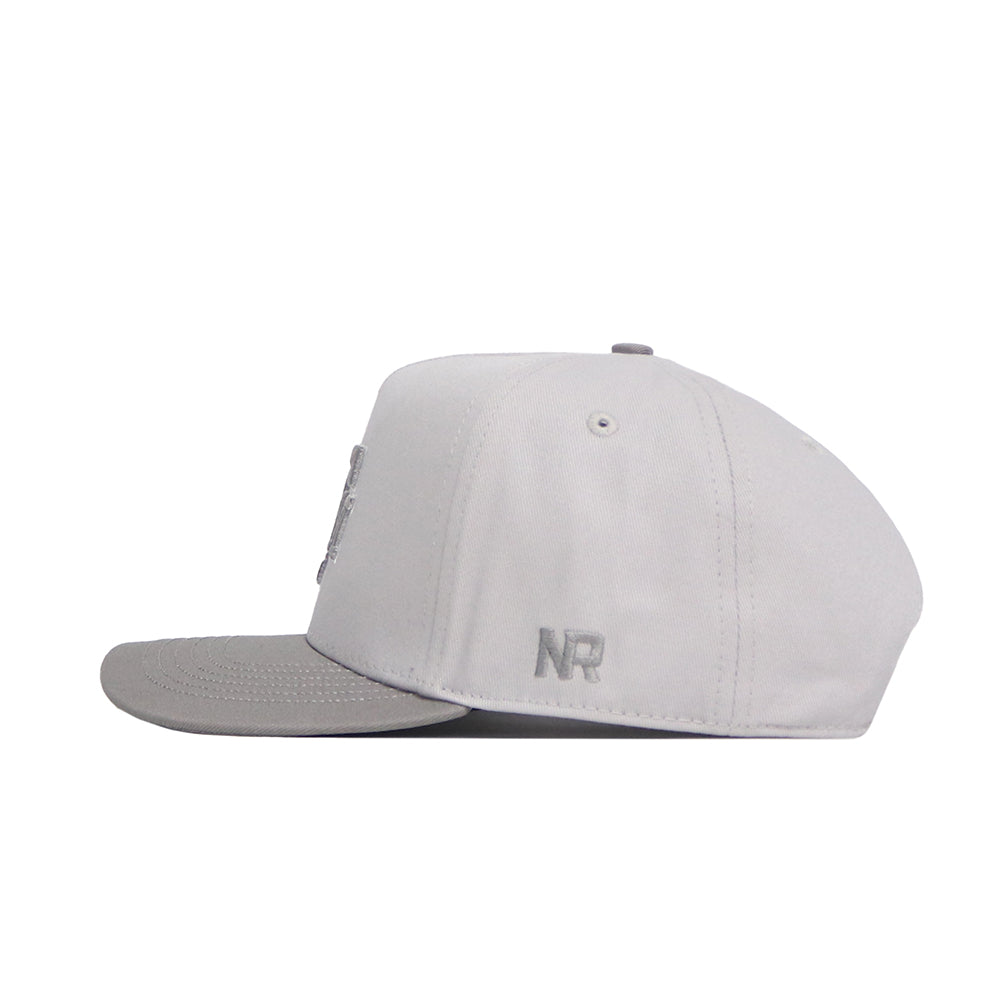 The No Rivals Texas A&M Graphite Hat is a light gray snapback with a structured fit, flat brim, and embroidered NR initials on the side, shown from a side profile against a white background.