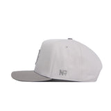The No Rivals Texas A&M Graphite Hat is a light gray snapback with a structured fit, flat brim, and embroidered NR initials on the side, shown from a side profile against a white background.