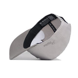 A Texas A&M Graphite Hat by No Rivals is shown flipped upside down, revealing a black-trimmed interior labeled NO RIVALS. "Aggies" is embroidered in gray on the outside of the brim.