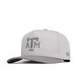 The Texas A&M Graphite Hat by No Rivals is a light gray snapback with a flat brim, featuring the embroidered ATM logo on the front and NFL logo on the side, made from high-quality cotton for a structured fit.