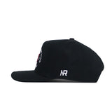 The Alabama Outlaw Hat - Black by No Rivals is shown in profile, made from high quality cotton, with white NR embroidery on the side near the back. The front and top are not visible from this angle.