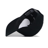 The Alabama Outlaw Hat - Black by No Rivals is shown upside down and tilted, revealing its structured inner lining with a QR code on the band and "NO RIVALS" printed on the inside.