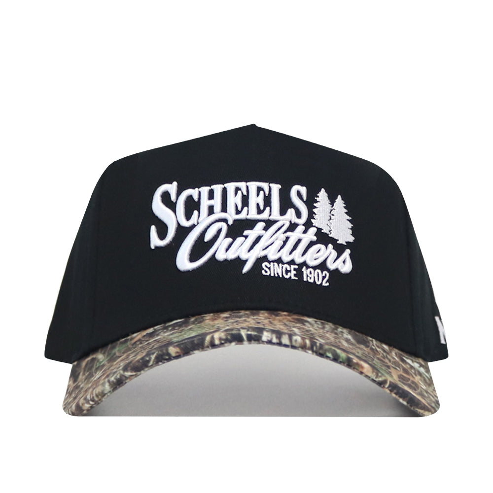 The Scheels Camo Trailblazer Hat features "SCHEELS Outfitters SINCE 1902" and two white tree graphics on the black front, plus a structured fit with a green and brown camouflage brim.